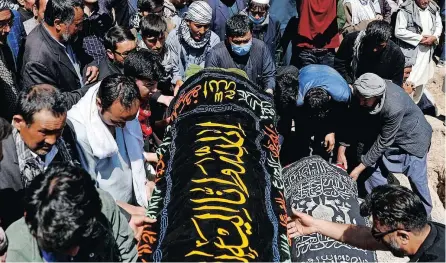  ?? AFGHAN mourners prepare victims’ coffins at a mass funeral ceremony in Kabul. | Reuters ??