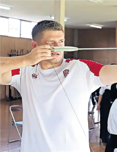  ??  ?? On target: Owen Farrell tries his hand at archery during a trip to a school