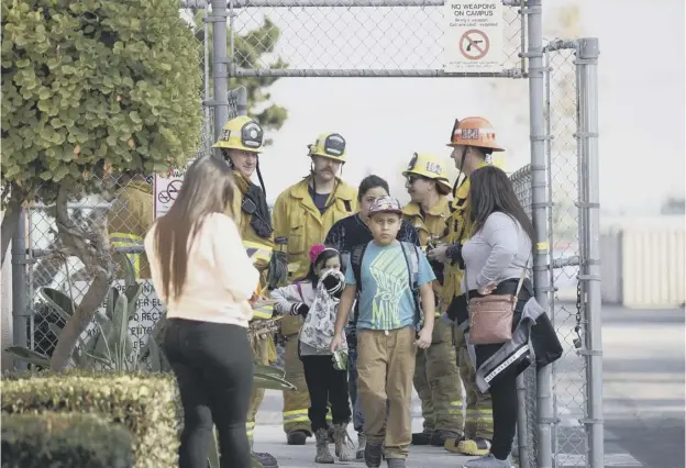  ??  ?? 0 Children evacuate the Park Avenue Elementary school in the city of Cudahy after an aircraft dropped fuel that fell onto the playground