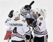  ?? HANNAH FOSLIEN/Getty Images ?? Teammates surround Blackhawks goalie Corey Crawford who has stopped 90 of 94 Minnesota shots in this series.