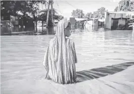  ?? LUIS TATO/AGENCE FRANCE-PRESSE ?? WOMAN wades through flood waters at an inundated residentia­l area in Garissa. Kenya is grappling with one of its worst floods in recent history following weeks of extreme rainfall that scientists have linked to a changing climate. At least 257 people have been killed and more than 55,000 households have been displaced as murky waters submerge entire villages, destroy roads and inundate dams.