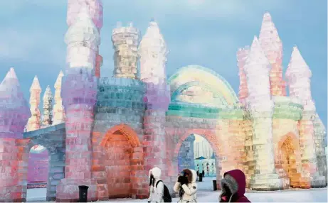  ??  ?? Winter wonderland: Visitors standing in front of ice sculptures illuminate­d by coloured lights at the annual ice festival in the northern city of Harbin.