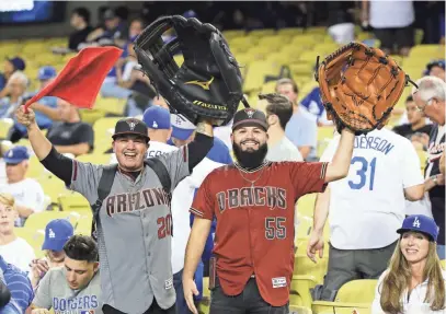  ?? ROB SCHUMACHER/THE REPUBLIC ?? Diamondbac­ks fans Xavier Escobedo (left) and Nore Ramon, both of Phoenix, display their oversized gloves Friday before Game 1 of the National League Division Series between the D-Backs and Dodgers at Dodger Stadium in Los Angeles.