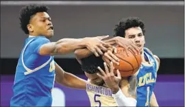  ?? Ted S. Warren Associated Press ?? JAYLEN CLARK, left, tries to grab a rebound from Washington’s Jamal Bey during UCLA’s ninth win in games decided by five points or fewer or in overtime.