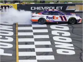  ?? (Getty Images) ?? Denny Hamlin, driver the #11 FedEx Toyota, celebrates with a sweet burnout Sunday after taking yet another race at Pocono.