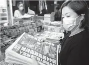  ?? ANTHONY KWAN/GETTY ?? A woman purchases multiple copies of the Apple Daily newspaper on Friday in Hong Kong.