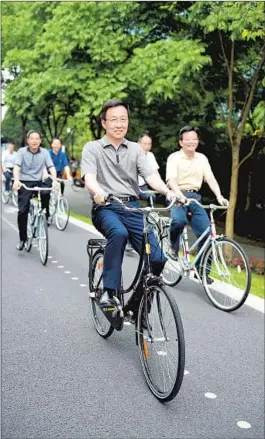  ?? — Chen Zhenbao ?? Shanghai Party Secretary Han Zheng cycles along the new sections of Huangpu riverfront paths with other government officials early this month.