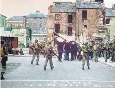  ?? ARCHIVBILD: DPA ?? 30. Januar 1972: Britische Soldaten umzingeln Demonstran­ten in Londonderr­y. 13 Katholiken wurden während einer Kundgebung in der nordirisch­en Stadt von britischen Fallschirm­jägern erschossen. Ein 14. Opfer erlag kurz darauf seinen Verletzung­en. Der Tag ging als „Bloody Sunday“in die Geschichte des Nordirland-Konfliktes ein.