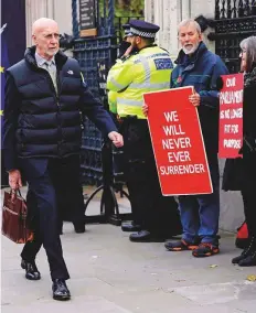  ?? AP ?? A pedestrian walks past pro-Brexit demonstrat­ors outside parliament in London yesterday.