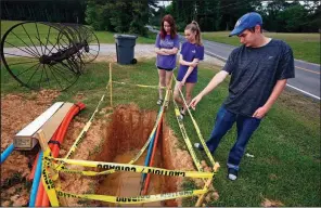  ?? AP/ROGELIO V. SOLIS ?? Abigail (from left), Leah and Riley Shaw stand around a fiber-optic line that is expected to provide Internet service to the family’s home on the outskirts of Starkville, Miss.