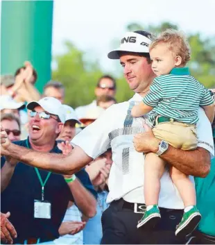  ?? AFP ?? Bubba Watson holds his son Caleb on the 18th green after winning the 2014 Masters via a three-stroke margin at Augusta National Golf Club course.