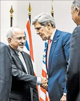  ?? FABRICE COFFRINI/GETTY-AFP PHOTO ?? Iranian Foreign Minister Mohammad Javad Zarif, left, shakes hands with Secretary of State John Kerry after world powers agreed to an interim deal with Iran early Sunday in Geneva.