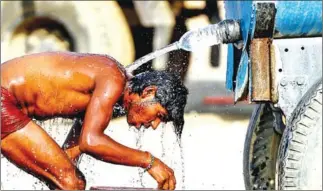  ?? SANJAY KANOJIA/AFP ?? An Indian truck driver takes a bath using a water tanker as he tries to cool himself on a hot summer afternoon in Allahabad.