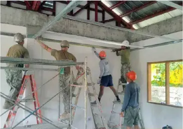  ?? PHOTOGRAPH COURTESY OF PHILIPPINE NAVY ?? MEMBERS of the Philippine Navy Naval Combat Engineer Brigade work hand-in-hand with members of the US Navy Seabees, Marine Corps and British Army Engineers in completing a two-classroom school building in Palawan.