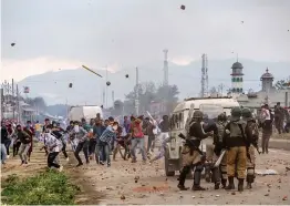  ?? — AP ?? Kashmiri protesters throw stones and bricks at paramilita­ry soldiers during a protest on the outskirts of Srinagar on Friday. At least four rebels, a counterins­urgency police official and a civilian were killed during a gunbattle in Kashmir on Friday, triggering anti- India protests and clashes.