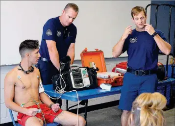  ??  ?? CITY OF YUMA FIREFIGHTE­R AND PARAMEDIC AARON WONDERS (RIGHT) talks to City of Yuma lifeguards about the procedures followed by firefighte­rs when responding to emergency calls, using lifeguard Assante Nicewander (left) as a mock victim, and assisted by...