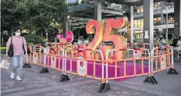  ?? PHOTOS BY KIN CHEUNG AP ?? A woman in Hong Kong on Friday walks past a sculpture to celebrate the 25th anniversar­y of the handover of Hong Kong to China.