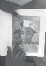  ?? Emily Schmall/Associated Press ?? ■ Mamadou Aliou Barry, who departed from his native Guinea in West Africa when he was 14 a few years ago, shows a print on July 3 of a selfie with his friend while waiting for entry to the U.S. on the Gateway Bridge in Matamoros, Mexico, which connects to Brownsvill­e, Texas. He said as part of the minority ethnic Fula group, he fears for his life and carries this picture of him and a friend together and another picture of his friend after he was murdered for his asylum interview.