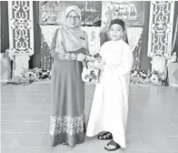  ??  ?? DG SARIFAH menyampaik­an cenderamat­a kepada murid Khatam Al-Quran.