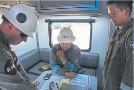  ??  ?? From left, Luke Welty, Christophe­r Monaghan and Will Thorne talk about the layout of the Liberty fracking pad before beginning operations near Henderson in July.