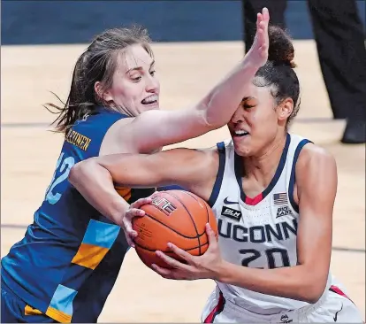  ?? JESSICA HILL/AP PHOTO ?? UConn’s Olivia Nelson-Ododa, right, drives to the basket as Marquette’s Lauren Van Kleunen defends during the first half of Monday night’s Big East tournament championsh­ip game at Mohegan Sun Arena. The top-ranked Huskies rolled to a 73-39.