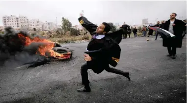  ??  ?? A Palestinia­n lawyer yesterday hurls stones towards Israeli troops during clashes at a protest against US President Donald Trump’s decision to recognise Jerusalem as the capital of Israel, near the Jewish settlement of Beit El, close to the West Bank city of Ramallah, yesterday.