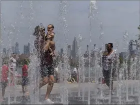  ??  ?? People enjoy the day playing in a water fountain as the Empire State Building is seen from Williamsbu­rg section of Brooklyn on Saturday, in New York. AP PHOTO/EDUARDO MUNOZ ALVAREZ