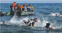  ??  ?? CENTRE OF DEBATE: Migrants swim ashore at Lesbos in Greece.