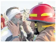  ?? AFP ?? A wounded man is checked by a fireman near the site of the explosion.