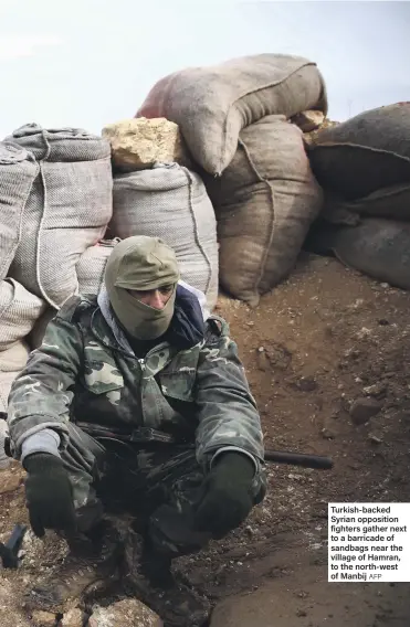  ?? AFP ?? Turkish-backed Syrian opposition fighters gather next to a barricade of sandbags near the village of Hamran, to the north-west of Manbij