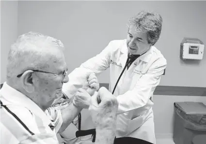  ?? KENNETH K. LAM/BALTIMORE SUN ?? Dr. Michael Miller checks the arm strength of patient Hank Butta, 89, at his office at the University of Maryland Medical Center. Miller helped craft recommenda­tions for a heart-healthy diet for the American Heart Associatio­n.