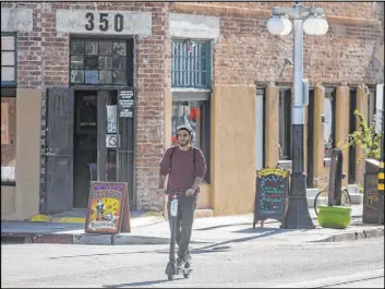  ?? Josh Galemore The Associated Press ?? A man rides a scooter Tuesday in Tucson, Ariz. Tucson officials are calling on the two e-scooter companies operating in the city to fix problems reported by groups.