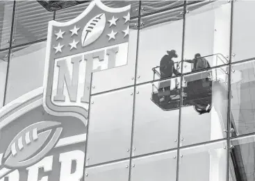  ?? Melissa Phillip / Houston Chronicle ?? Workers prepare a sign outside the George R. Brown Convention Center, one of the hundreds of venues in the Houston area booked for Super Bowl events.