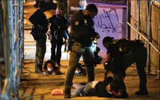  ?? HYOSUB SHIN / HYOSUB.SHIN@AJC.COM ?? Atlanta Police arrest people on downtown streets after curfew Saturday, including some seen vandalizin­g property. Mayor Keisha Lance Bottoms implemente­d the curfew after a night of chaos and looting followed peaceful protests Friday, and extended the restrictio­ns.