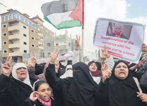  ??  ?? Palestinia­ns raise national flags and banners during a demonstrat­ion against a U.S.-drafted resolution in the town of Rafah in the southern Gaza Strip, Dec. 6.