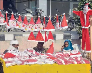  ?? — AFP ?? Vendors sell Santa Claus hats and masks on a roadside in Amritsar on Thursday. Christmas is celebrated with much fanfare and zeal throughout the country.