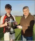  ??  ?? Dermot ‘Weeshie’ Lynch presents the Joe O’Connor Cup to Colmain O’Meara, Gaelcholai­ste captain