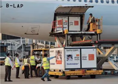  ??  ?? Airport workers unload the first batch of China’s Sinovac Biotech CoronaVac vaccine from an aircraft after it arrived at Hong Kong Internatio­nal Airport on Friday. — AFP