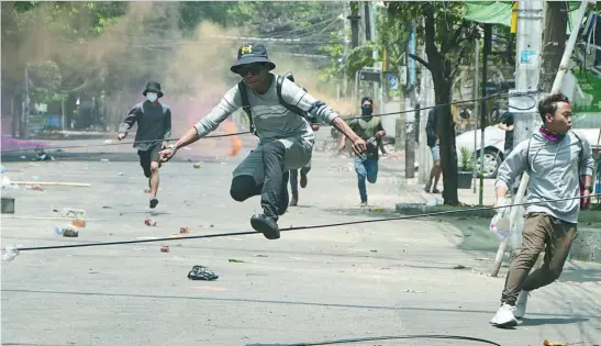  ?? AP ?? Varios jóvenes antigolpis­tas corren para huir de las Fuerzas Armadas, ayer, en Yangon