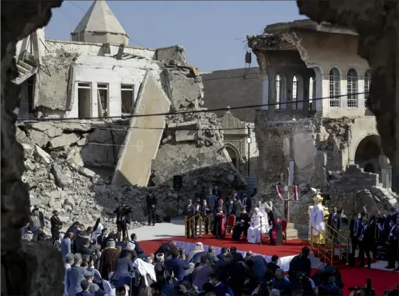  ?? Andrew Medichini/Associated Press ?? Pope Francis, surrounded by shells of destroyed churches, leads a prayer for the victims of war Sunday at Hosh al-Bieaa Church Square in Mosul, Iraq, once the de facto capital of the Islamic State group. The long war to drive out IS left ransacked homes and pulverized buildings around the north of Iraq, sites Francis visited on Sunday, the final day of his historic trip to the troubled Mideast nation.