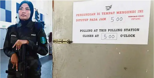  ?? Bernama ?? Standing guard: Special force police officer Zuliana Zulkipli is already on duty to ensure safety when the personnel of the 4th Battalion of the General Operations Force start the voting process to pick the Semenyih representa­tive today.—