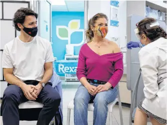  ?? REUTERS ?? Canada’s Prime Minister Justin Trudeau watches as his wife Sophie Gregoire is inoculated with Astrazenec­a’s vaccine against COVID-19 at a pharmacy in Ottawa on April 23.