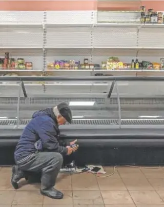  ?? // EFE ?? Un hombre carga su teléfono en un supermerca­do a las afueras de Jersón