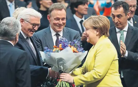  ?? ODD ANDERSEN / AFP ?? La canciller Angela Merkel entrega un ramo de flores a Frank-Walter Steinmeier nada más ser elegido presidente federal en el Bundestag