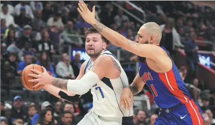  ?? AP ?? Luka Doncic of the Dallas Mavericks goes on the attack as Evan Fournier of the Detroit Pistons defends during an NBA game on Saturday in Detroit. Doncic piled on 39 points, 10 rebounds and 10 assists to set an NBA-record sixth straight 30-point triple-double.