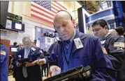  ?? RICHARD DREW / AP ?? Trader Daniel Leporin (center) works on the floor of the New York Stock Exchange on Wednesday. Investors snapped up high-dividend utilities and real estate investment trusts as bond yields fell.