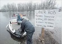  ?? ANDREW VAUGHAN THE CANADIAN PRESS ?? Rob Dekany, known locally as Uber Rob, ferries stranded passengers at Darlings Island, N.B., after the Kennebecas­is River flooded the only road into the community. Dekaney has been offering the service all week.