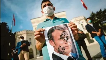  ?? Foto: dpa ?? Ein junger Mann hält in Istanbul ein mit einem Schuhabdru­ck versehenes Foto von Frankreich­s Präsident Emmanuel Macron in die Kamera. Der türkische Staatschef Recep Tayyip Erdogan warf Macron erneut Islamfeind­lichkeit vor.