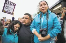  ??  ?? Eusebio Sanchez embraces his daughters Elizabeth Sanchez (left) and Melin Sanchez as hundreds of people chant in support of the family outside Highland Hospital.