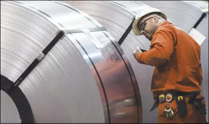  ?? CP PHOTO ?? A Dofasco employee looks at rolls of coiled steel in Hamilton Ont. The Trump administra­tion says it will go ahead with plans to hit Canada, Mexico and the European Union with hefty tariffs on steel and aluminum.